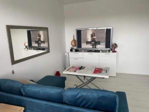 uma sala de estar com um sofá azul e uma televisão em Appartement calme et ensoleillé em Hérouville-Saint-Clair
