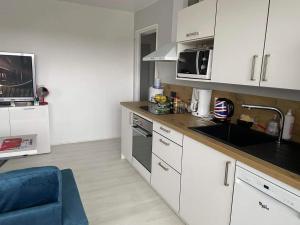 a kitchen with white cabinets and a sink and a blue chair at Appartement calme et ensoleillé in Hérouville-Saint-Clair