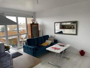 uma sala de estar com um sofá azul e uma mesa em Appartement calme et ensoleillé em Hérouville-Saint-Clair