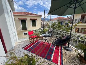 a balcony with a table and chairs and an umbrella at Thalgiron, a breath away from Delphi in Ámfissa