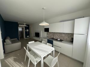 una cucina con tavolo bianco e sedie bianche di Woody Green Charming Apartments - Agenzia Cocal a Caorle