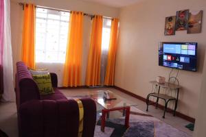 a living room with a couch and a tv at Chaka Homes in Kiganjo