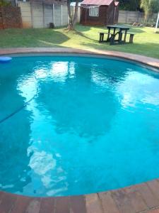 uma piscina azul com uma mesa de piquenique ao fundo em Anglerfish em Centurion