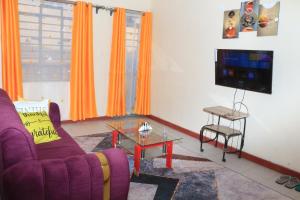 a living room with a purple couch and a tv at Chaka Homes in Kiganjo
