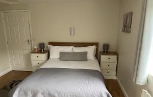 een slaapkamer met een bed, 2 dressoires en een deur bij Cherry Tree Cottage in idyllic Cotswold village in Chipping Norton