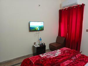 a bedroom with a bed and a chair and a television at Second Home Family Hotel in Lahore