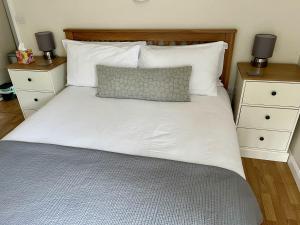 1 cama con sábanas y almohadas blancas y 2 mesitas de noche en Cherry Tree Cottage in idyllic Cotswold village, en Chipping Norton