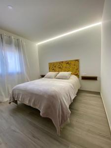 ein weißes Schlafzimmer mit einem großen Bett mit einem Kopfteil in der Unterkunft Casa de Goya in Argés