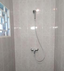 a shower with a hose attached to a tiled wall at Chez Nous in Pointe-Noire