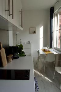 cocina blanca con mesa y comedor en Studio calme et cosy au Andelys pour 2 personnes en Les Andelys