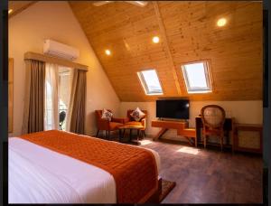 a bedroom with a bed and a desk and a television at Samsara Luxury Cottages & Spa !! Best Resort in Chail in Chail