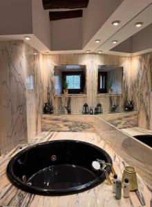 La salle de bains est pourvue d'une baignoire noire et de murs en marbre. dans l'établissement Mas Feliu Turismo Rural, à Pujals dels Cavallers