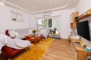 uma sala de estar com um sofá e uma televisão em Apartman Mehic em Crikvenica