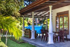 un patio con mesa y sillas bajo una pérgola en MAKAI Surf House en Ahangama