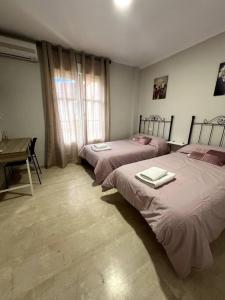 a bedroom with two beds and a table and a desk at Casa para grupos en Granada in Granada