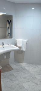 Baño blanco con 2 lavabos y espejo en Hostal Europa en Tarragona