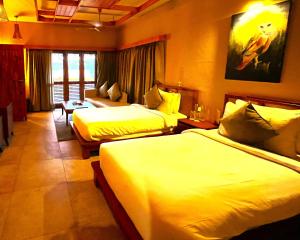 Habitación de hotel con 2 camas y sofá en Hotel Sonar Bangla Sundarban, en Gosāba