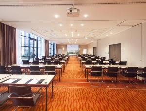 a room with rows of tables and chairs in a room at Steigenberger Dortmund in Dortmund