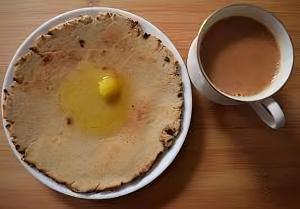 a pie with an egg in a bowl next to a cup of coffee at Renewed Jadeshwar Farm Resort in Sasan Gir