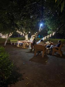 personas sentadas en bancos en un parque por la noche en Renewed Jadeshwar Farm Resort, en Sasan Gir