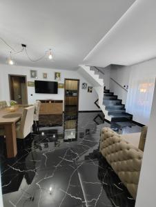 a living room with a staircase and a table and chairs at Black&White House in Ocna-Mureşului