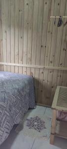 1 dormitorio con 1 cama y pared de madera en Vista da lagoa en Laguna