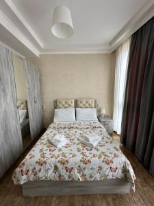 a bedroom with a bed with a floral bedspread at Rustaveli Apartment 113 in Kutaisi