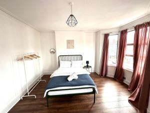 a bedroom with a bed and two windows at Charming, Renovated Residence in Willesden Green in London