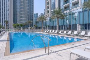 a large swimming pool with chairs and a building at Heaven Crest Holiday Homes - Luxury Forte in Dubai