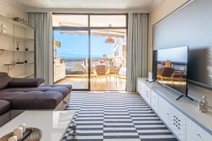 uma sala de estar com um sofá e uma televisão em Ocean View Sunset Apt by Dream Homes Tenerife em Puerto de Santiago