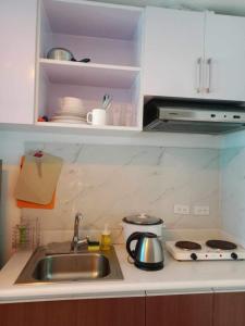 a kitchen counter with a sink and a stove at Cozy Condo near US EmbassyErmita Manila/ Roxas blvd/ Dolomite beach in Manila