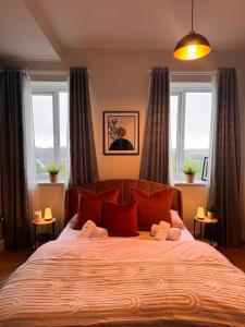 a bedroom with a large bed with red pillows and windows at Finnstown Hall in Dublin
