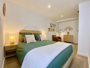 a bedroom with a green and white bed and a chair at Montignac-Lascaux - Les Pierres De Lascaux in Montignac