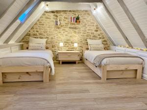 een slaapkamer op zolder met 2 bedden en een stenen muur bij Montignac-Lascaux - Les Pierres De Lascaux in Montignac