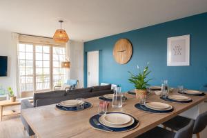 a dining room with a wooden table and blue wall at Le Noyer - moderne - spacieux - parking in Montaigu-Vendée