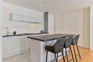 a kitchen with white cabinets and black counter stools at Coeur de Presqu’île Hotel Dieu in Lyon