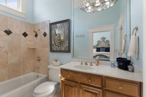a bathroom with a sink toilet and a mirror at Sea-Esta - 1136 Postell in East End