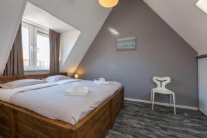 a bedroom with a large bed and a chair at Vakantiewoning in centrum Zoutelande, bij het strand in Zoutelande