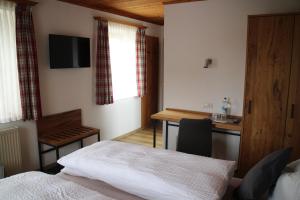 a bedroom with a bed and a desk with a television at Gasthaus zum Stausee in Grafenau