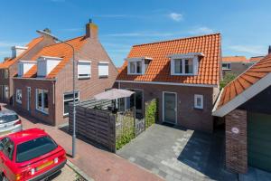 a red car parked in front of a brick house at Vakantiewoning in centrum Zoutelande, bij het strand in Zoutelande