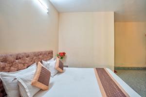 a bedroom with a bed with white sheets and pillows at Golden Studio Apartment Goa in Calangute