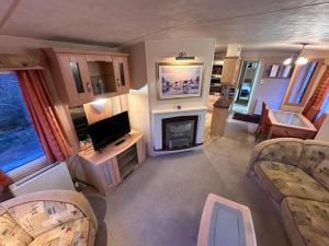 a living room with a television and a fireplace at Atlas 2 Bedroom Caravan, Glasgow in Uddingston
