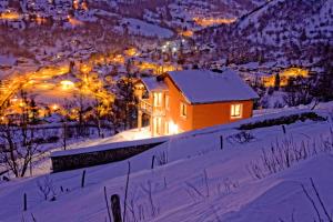 a house in the snow at night with lights at La Grange des Mios in La Bresse