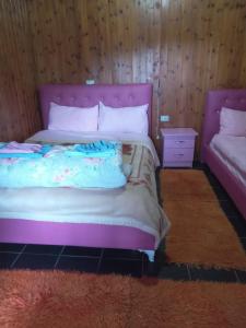 un letto con testiera rosa e comodino di GuestHouse Hamiti Llogara a Vlorë