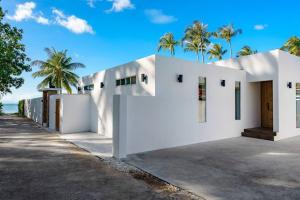 une maison blanche avec des palmiers en arrière-plan dans l'établissement 塔羅别墅-直通海滩的三卧海滨别墅, à Koh Samui 