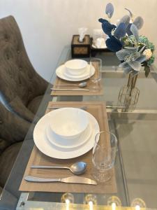 a glass table with plates and silverware on it at Service Apartment ใจกลางเมืองใกล้แหล่งท่องเที่ยว119ทับ1ถนนปงสนุก in Lampang