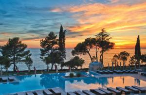 a swimming pool with a sunset in the background at Hotel Parentium Plava Laguna in Poreč