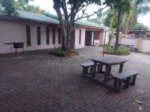a picnic table and bench in front of a building at Nomanini guest house Nelspruit in Nelspruit