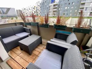 a balcony with couches and chairs and potted plants at Loft Industriel à côté de La Défense in Nanterre