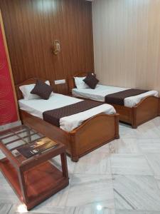 two beds in a room with a table at HOTEL RIZ VARANASI in Varanasi